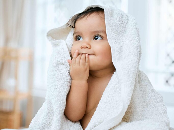 Aufnahme eines entzückenden Babys, das nach dem Baden mit einem Handtuch bedeckt ist | © Getty Images/PeopleImages