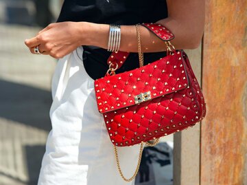 Rote Tasche mit Nieten am Handgelenk einer Frau | © Getty Images/Elena Boltunova