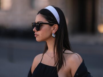 Streetstyle von Frau mit langen, braunen Haaren mit schwarzem Haarband, schwarzer Sonnenbrille und schwarzem Top | © Getty Images/Jeremy Moeller