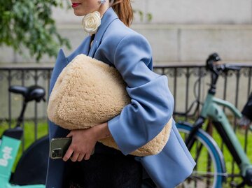 Modisch gekleidete Frau mit großer XL-Clutch im Fake-Fur-Look | © Getty Images/Christian Vierig