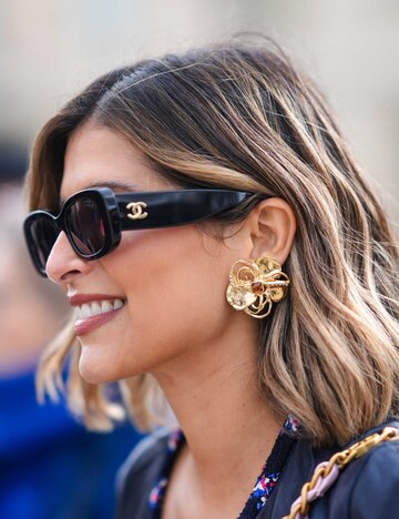 Frau trägt Sonnenbrille und goldenen Schmuck | © Getty Images/Edward Berthelot 