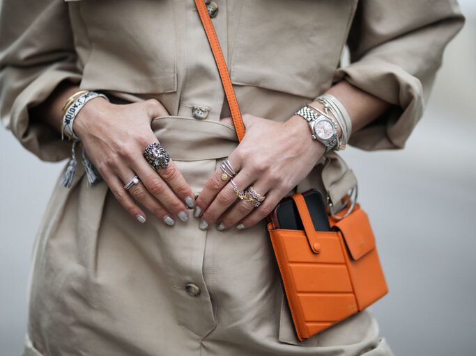 Frau hält ihre Hände und Arme voller Schmuck vor ihrer beigen Jacke | © Getty Images/Jeremy Moeller 