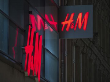 H&M-Filiale mit beleuchtetem Logo bei Nacht | © Getty Images/Michael Gottschalk/Photothek 