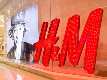 Das H&M Logo hinter einem Schaufenster in einem Einkaufszentrum. | © Adobe Stock/ThamKC