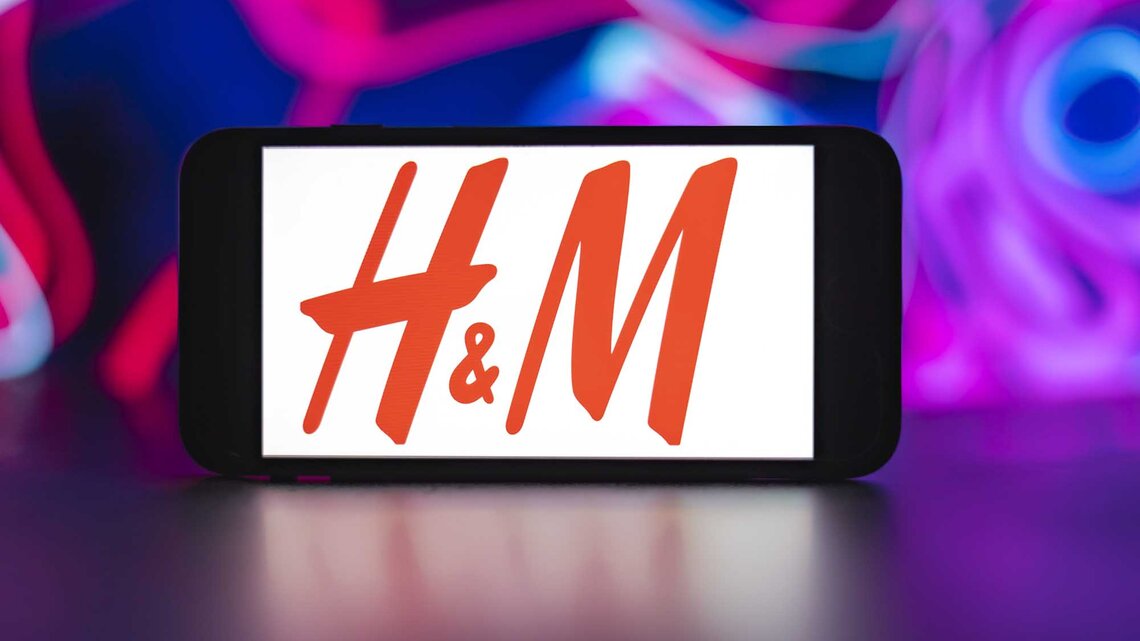 H&M Logo auf einem Handybildschirm vor einem bunten Hintergrund. | © Getty Images/SOPA Images