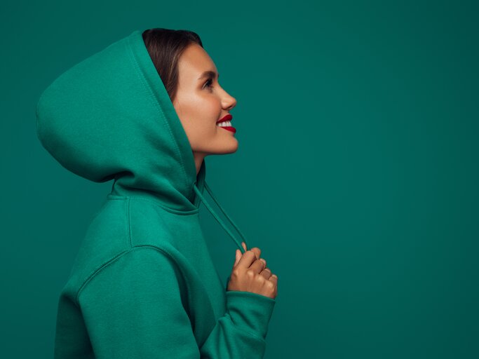 Schöne Frau im grünen Hoodie | © Getty Images/	CoffeeAndMilk