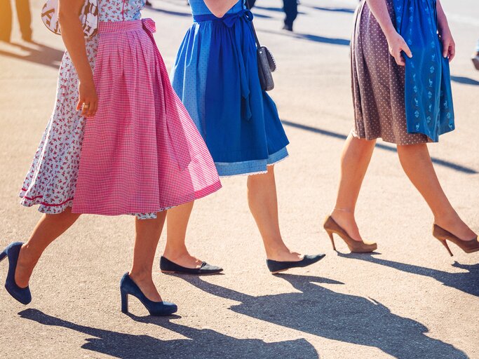 Frauen mit Dirndl und verschiedenen Schuhen gezeigt ab der Hüfte abwärts | © GettyImages/Nikada