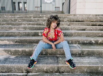 Junge Frau sitzt mit futuristischen Sneakern auf einer Treppe | © Getty Images/Westend61