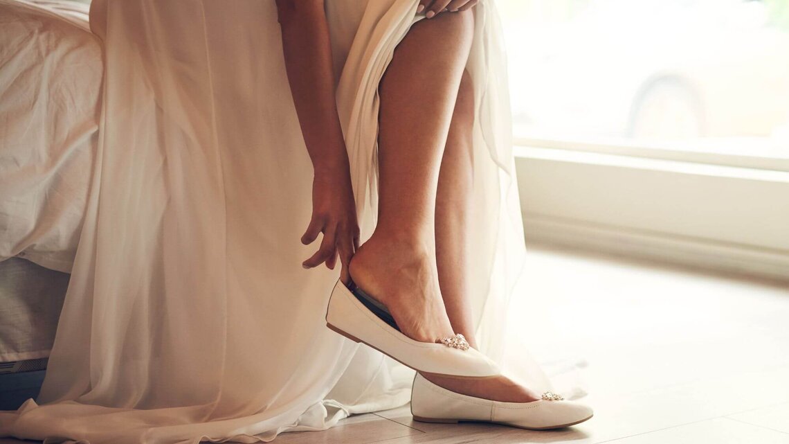Braut zieht Ballerinas an | © Getty Images/Hiraman
