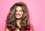 Frau mit voluminösen Haaren vor einem pinken Hintergrund | © gettyimages.de | Ada Summer