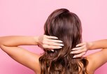 Frau mit brauen, welligen Haaren von hinten vor pinkem Hintergrund fotografiert | © gettyimages.de | Deagreez