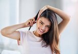 Frau mit schönen Haaren und breitem Lachen bürstet sich die Haare | © gettyimages.de | PeopleImages