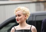 Julia Garner trägt blonde kurze Locken und ein schwarzes Lederkleid. | © Getty Images / Edward Berthelot 