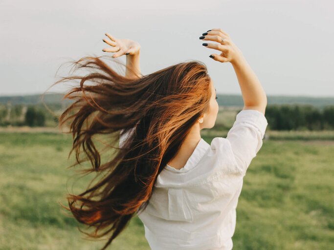 Nahaufnahme Porträt von einer Frau mit schönen, langen Haaren auf dem Feld, Blick von hinten.  | © gettyimages.de | Galina Zhigalova