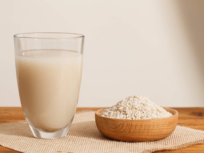 Glas mit Reiswasser neben einer Holzschale mit Reis | © gettyimages.de | Guiyuan