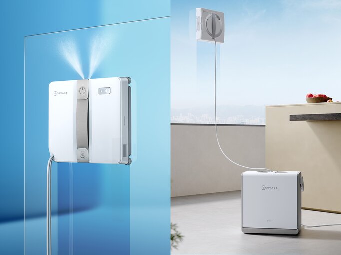 Zwei moderne Fensterputzroboter von ECOVACS, einer mit beige-grauem Griff, der andere mit silbernem Griff, auf Glasscheiben. | © ECOVACS