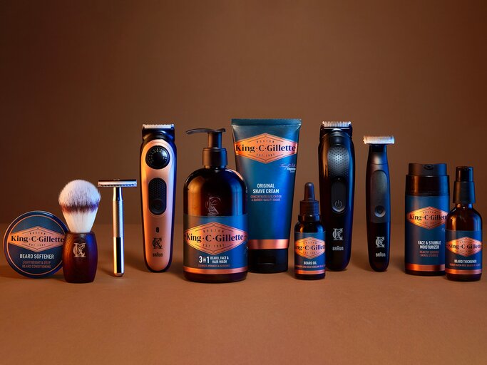 Reihe mit Bartpflegeprodukten und Rasierern von King C. Gillette und Braun vor braunem Hintergrund arrangiert. | © King C. Gillette 