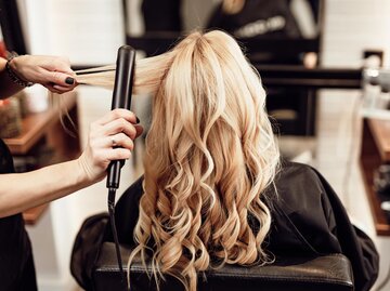 Frau mit blonden Locken bekommt von Friseurin die Haare gestylt | © AdobeStock/hedgehog94