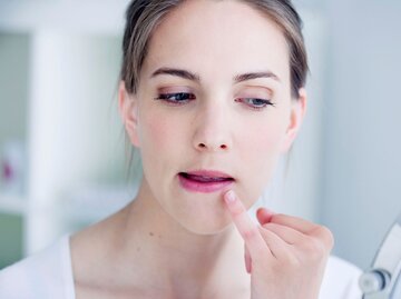 Frau begutachtet ihre Lippe im Spiegel | © Adobe Stock/RFBSIP