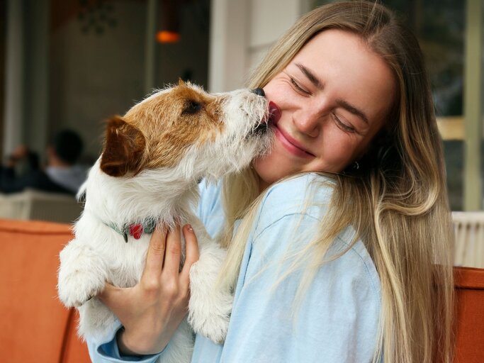 Junge Frau kuschelt mit einem kleinen Hund | © Adobe Stock/Evrymmnt