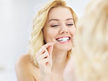Frau benutzt Zahnseide | © iStock | macniak