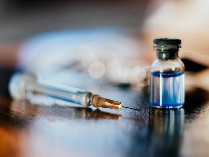 Eine Spritze liegt neben einem Medikament auf einem Tisch. | © Getty Images / Guido Mieth