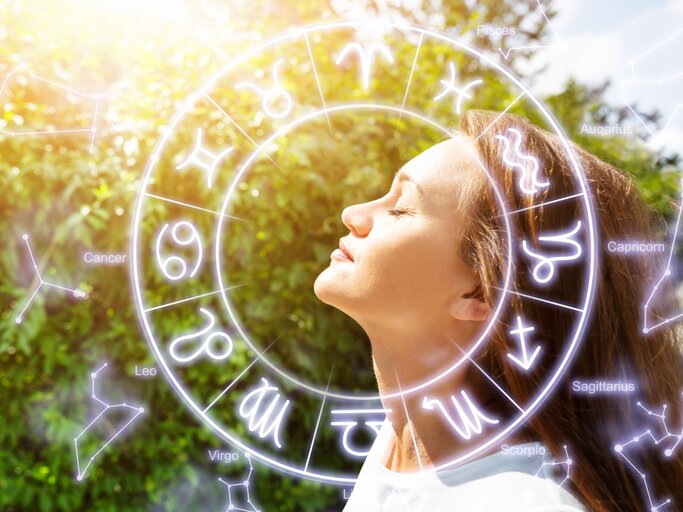 Frau blickt in den sonnigen Himmel, Tierkreiszeichen | © Getty Images/AndreyPopov