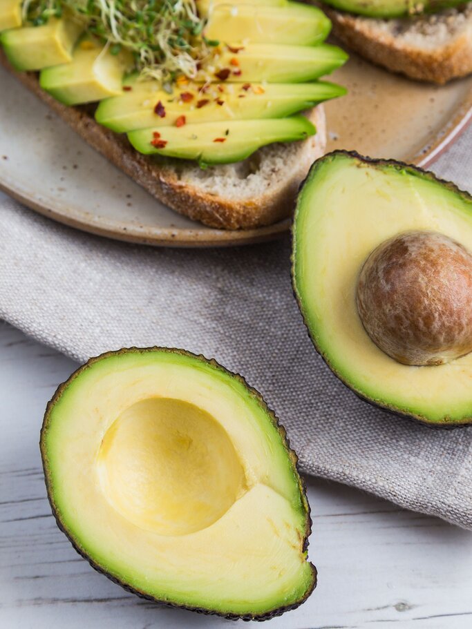 aufgeschnittene Avocado und Avocado-Brot | © iStock | locknloadlabrador