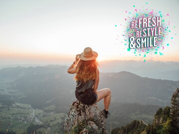 Junge Frau auf einem Berg blickt in den Sonnenuntergang | © Getty Images/Westend61