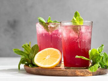 Hibiskuseistee mit Zitrone, Minze und Eis in Gläsern auf grauem Steinhintergrund | © gettyimages.de | porosolka