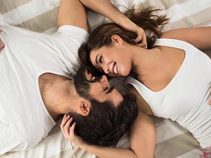 Junges Paar liegt verliebt im Bett und schaut sich Überkopf an | © shutterstock/Goksi