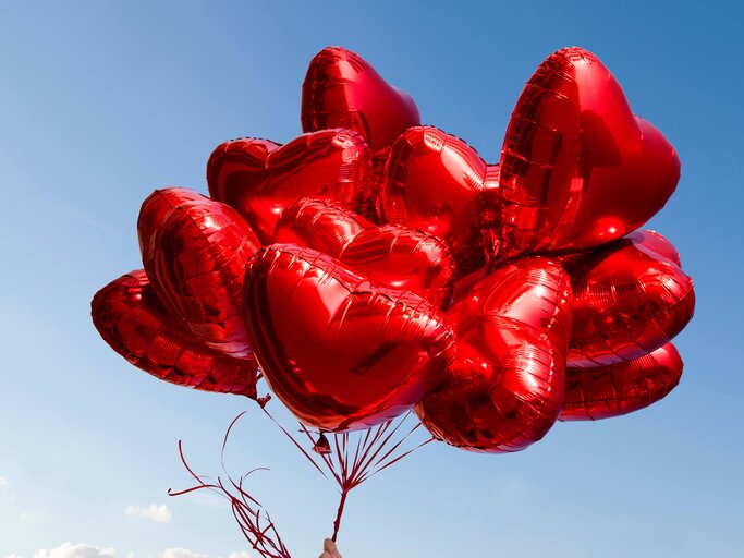 Rote Herzluftballons vor blauem Himmel | © gettyimages.de | Christian Adams