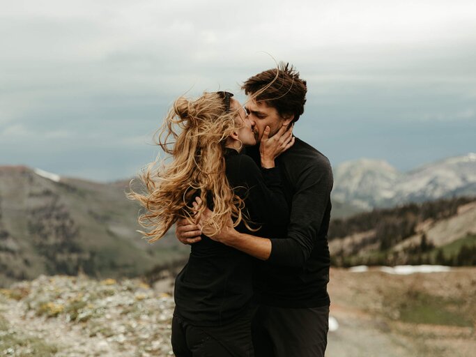 Paar küsst sich im Wind auf einem Berg | © gettyimages.de | Cavan Images