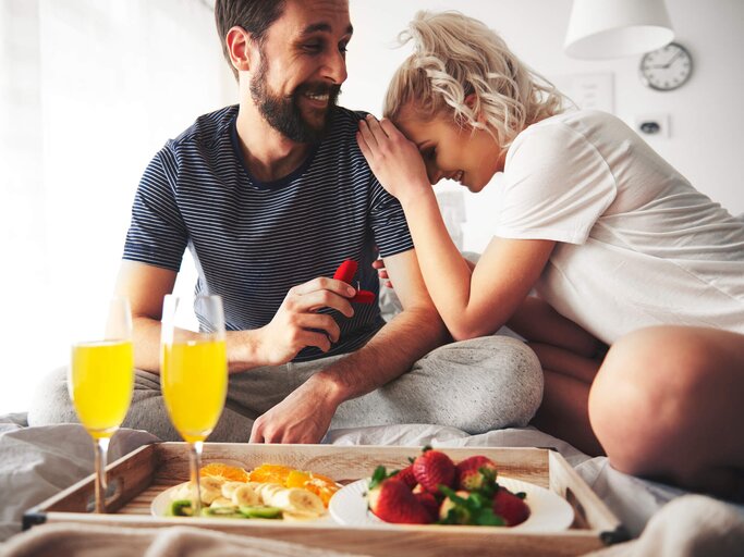 Mann macht seiner Freundin beim Frühstück am Bett einen Heiratsantrag | © gettyimages.de | Gpointstudio