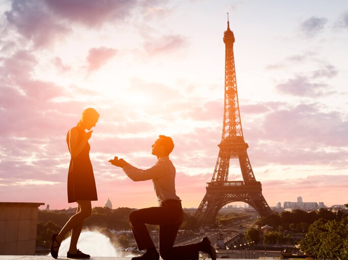 Mann kniet vor seiner Freundin und macht ihr vor dem Eiffeltum einen Antrag. | © gettyimages.de | NicoElNino