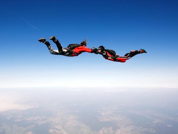 Paar im freien Fall beim Fallschirmsprung vor blauem Himmel | © gettyimages.de | vuk8691