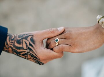 Tattoowierte Hand hält Hand mit Verlobungsring | © gettyimages.de | Sara Monika