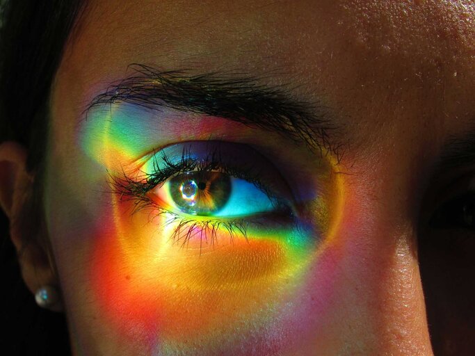 Das Auge einer Frau ist mit bunten Farben beleuchtet. | © Getty Images / Joana Rodrigues - EyeEm