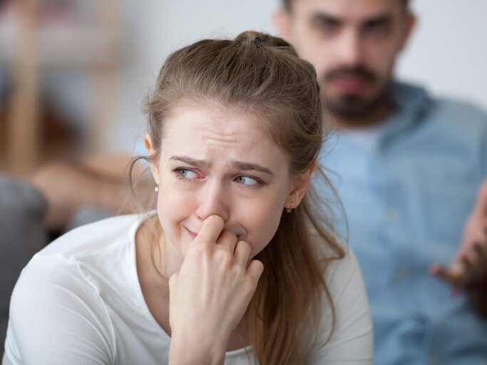 Junge Frau weint, im Hintergrund ist Mann zu sehen | © gettyimages.de| fizkes