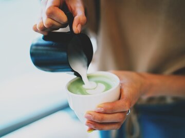 Frau gießt aufgeschäumte Milch in ihren Matcha Latte | © shutterstock / JKstock
