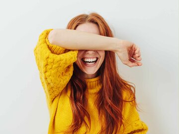 Frau hält sich vor Lachen den Arm vor das Gesicht | © Getty Images/stockfour