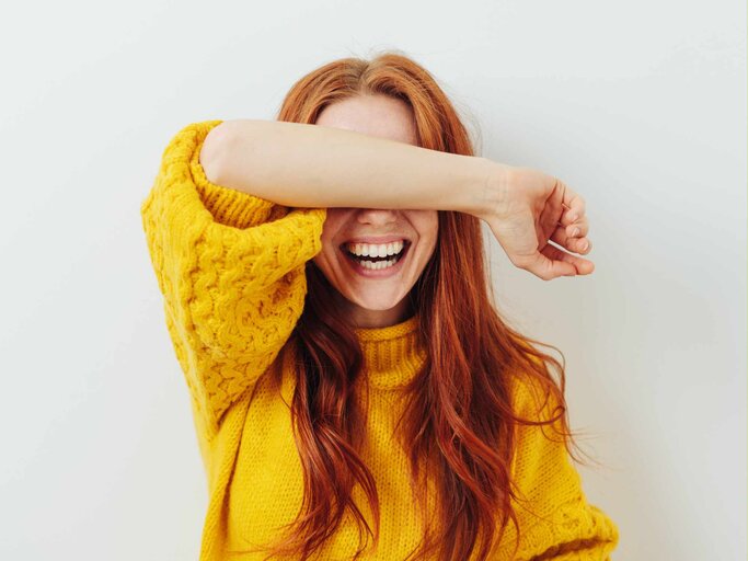 Frau hält sich vor Lachen den Arm vor das Gesicht | © Getty Images/stockfour
