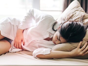 Frau liegt mit Unterleibsschmerzen im Bett | © gettyimages.de / Thnathip Pha Tir Wat'hn / EyeEm