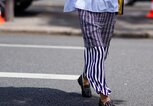 Detailaufnahme einer Besucherin der Menswear Fashion Week in Paris mit Print-Rock und Nieten-Loafern | © Getty Images / Edward Berthelot