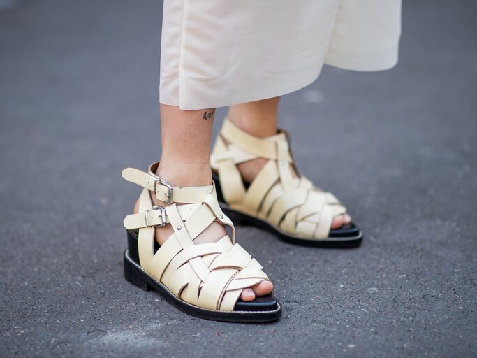 Detailaufnahme des Streetstyles einer Besucherin mit flachen Riemchensandlen in Creme von Acne Studios und einer cremefarbenen Culotte bei der Haute Couture Fashion Week in Paris | © Getty Images / Christian Vierig