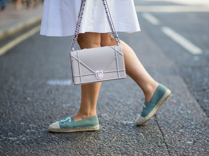 Streetstyle einer Besucherin in weißem Kleid, türkisfarbenen Chanel-Espadrilles und mit Dior Handtasche bei der Menswear Fashion Week in London | © Getty Images / Christian Vierig