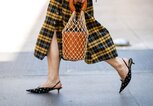 Detailaufnahme einer Besucherin in kariertem Rock und Kitten Heels mit Beuteltasche auf der Menswear Fashion Week in Mailand | © Getty Images / Christian Vierig