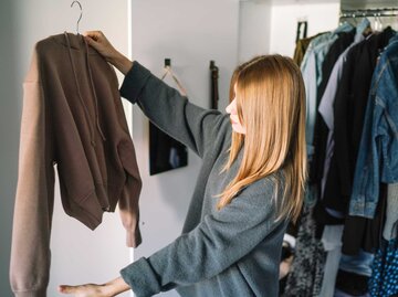 Frau hält Kleiderbügel mit Pulli nach oben | © Getty Images/All Nea / 500px