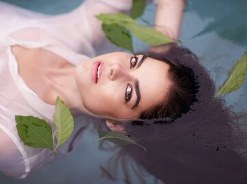 Frau, die im Wasser schwimmt mit Blättern | © iStock | Tassii