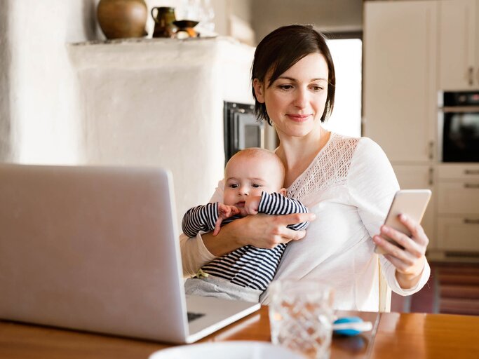 Frau mit Baby auf dem Arm und Handy | © iStock | GrapeImages